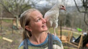 Tara Newby stands with a chicken on her shoulder.